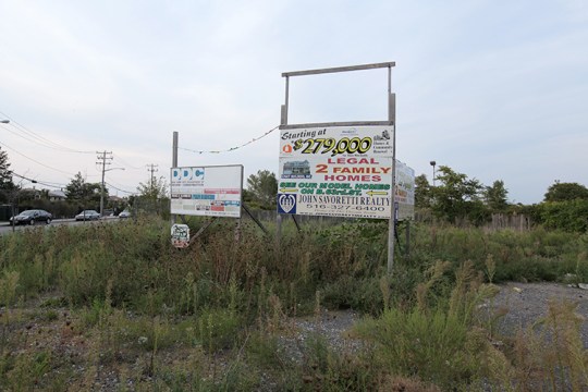An overgrown lot advertising yet another housing development.